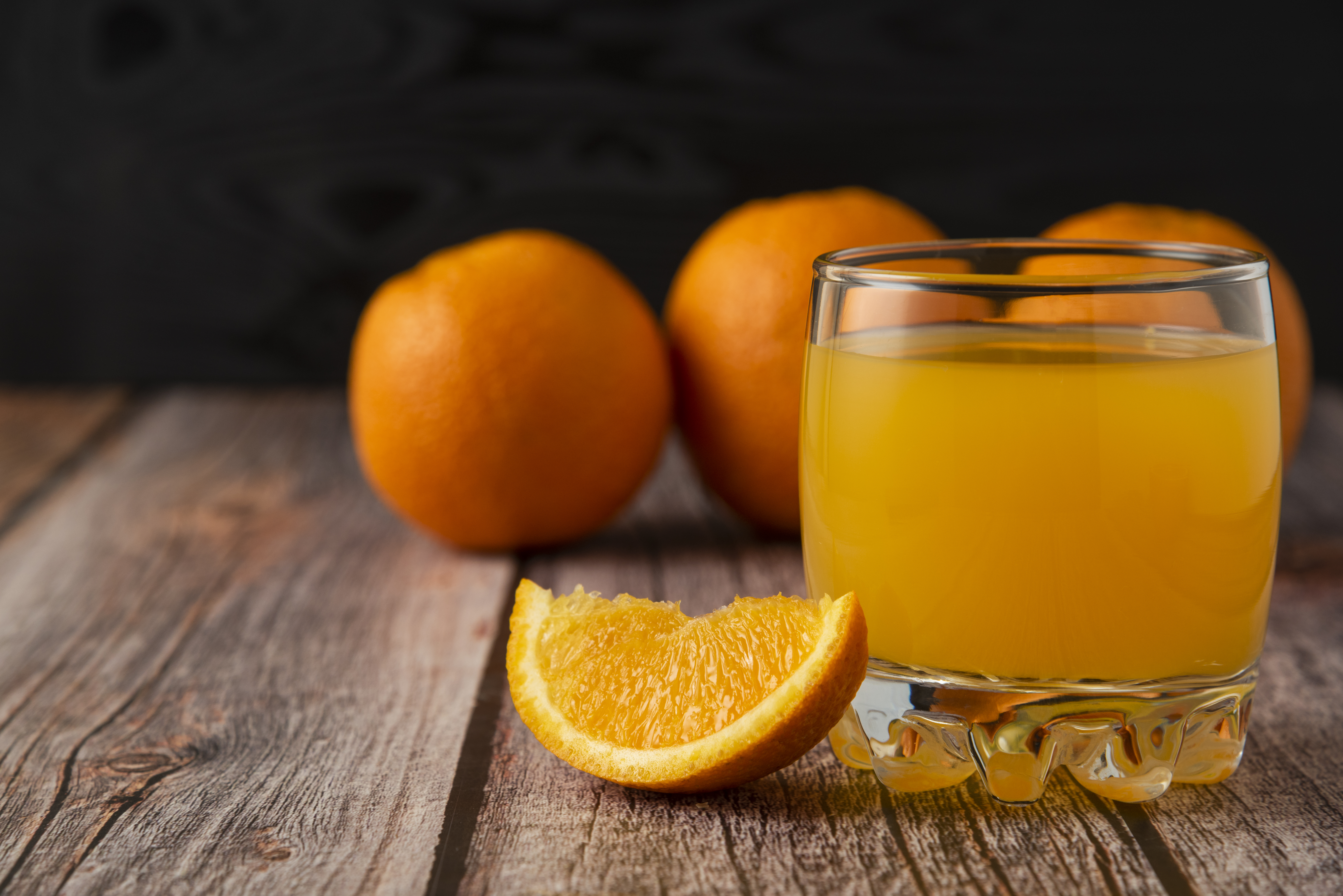 Orange fruit with a glass of juice on the wooden table. High quality photo