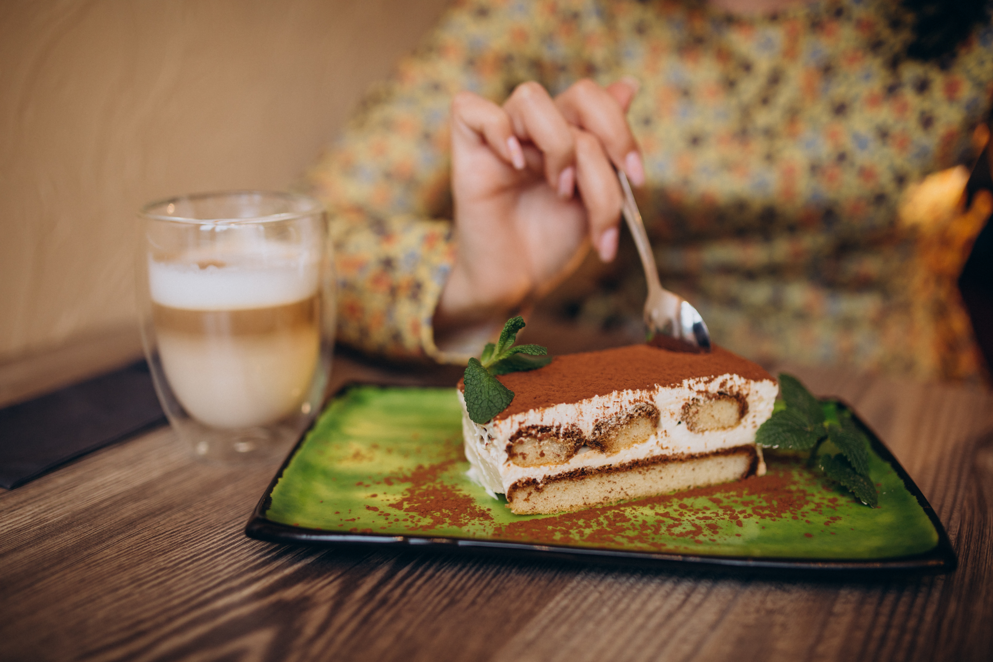 Young woman eating delicious tiramisu in a cafe